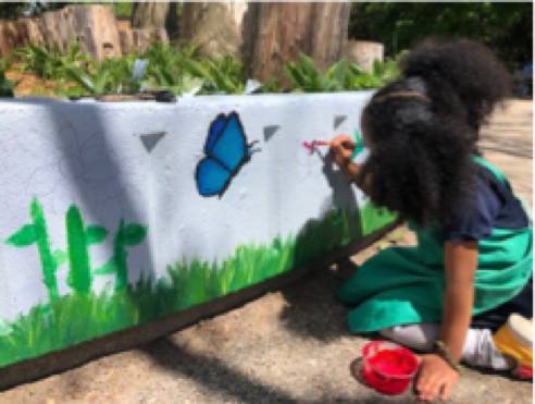 student painting butterfly on the Shawmut Hills sycamore circle mural